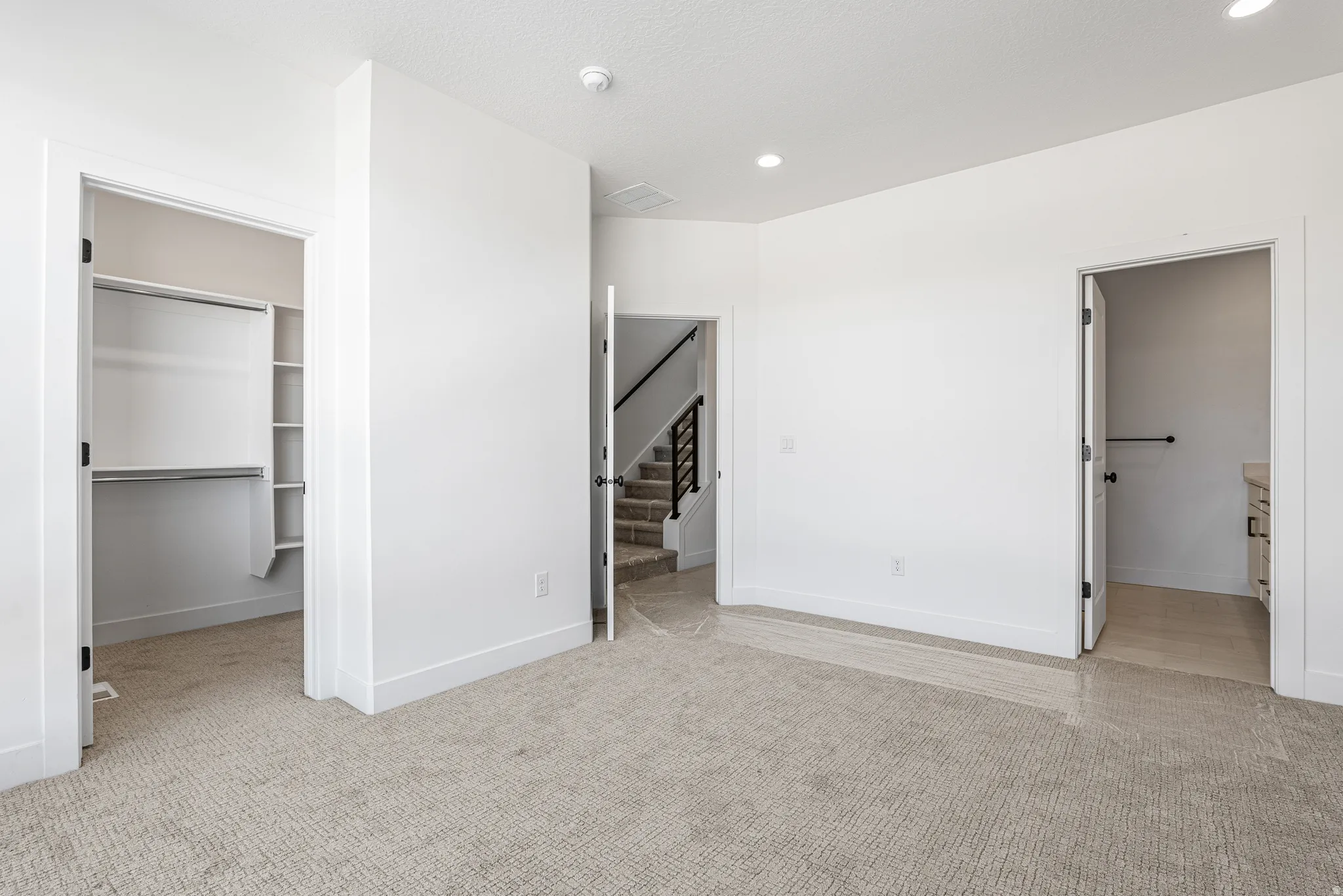 Carpeted room with white walls, featuring a walk-in closet with shelving and hanging rods