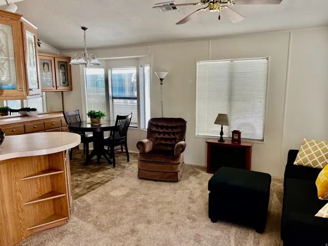 Living room with crown molding, light carpet, hanging lights, and a ceiling fan