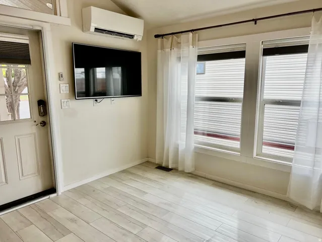 Entryway with a wall mounted air conditioner, plenty of natural light, and light wood-type flooring