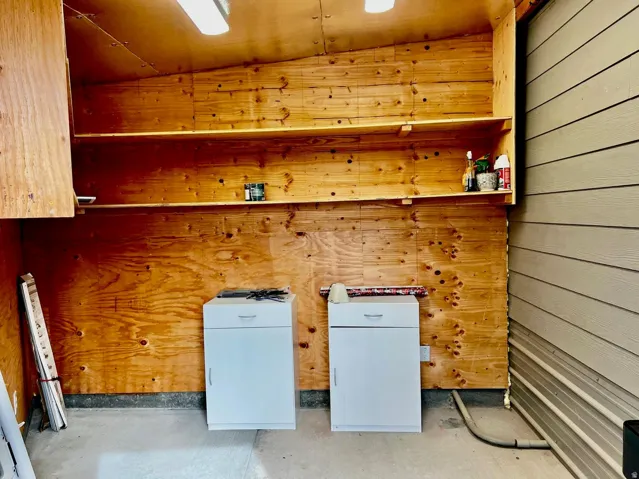 Laundry area featuring wooden walls and vaulted ceiling