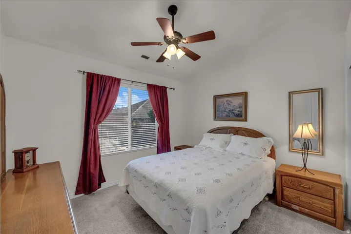 Carpeted bedroom with lofted ceiling and ceiling fan