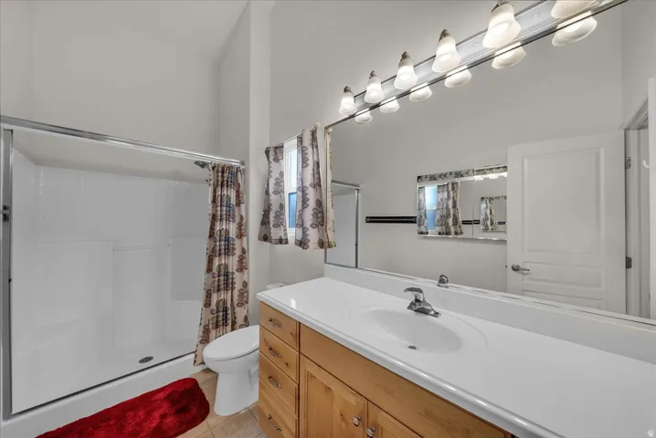 Full bathroom with a stall shower, vanity, and light tile patterned flooring
