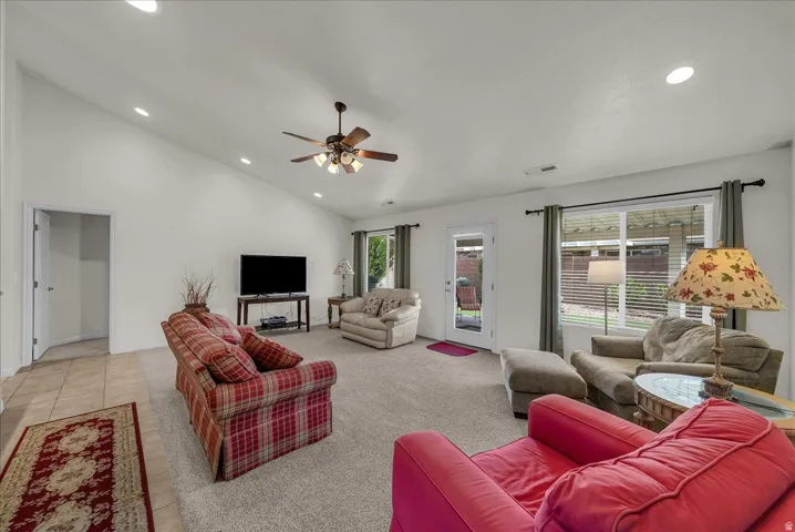 Carpeted living room featuring recessed lighting, ceiling fan, high vaulted ceiling, and tile patterned floors