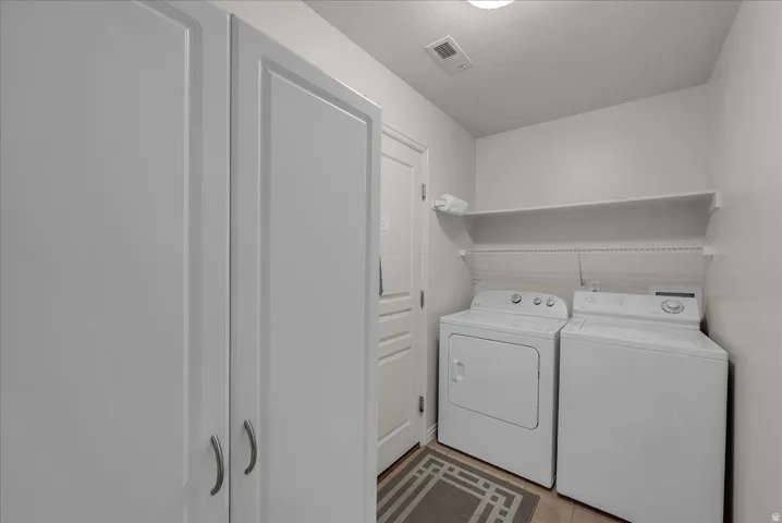 Laundry area featuring independent washer and dryer and light tile patterned floors