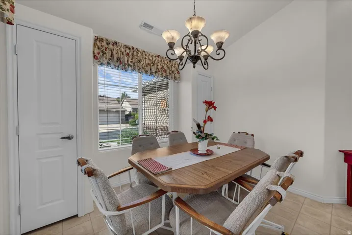 Dining area featuring light tile patterned floors, a chandelier, and vaulted ceiling