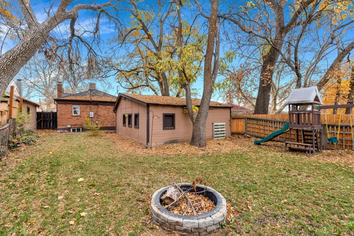 Fenced backyard featuring a playground, an outdoor fire pit, and an outdoor structure