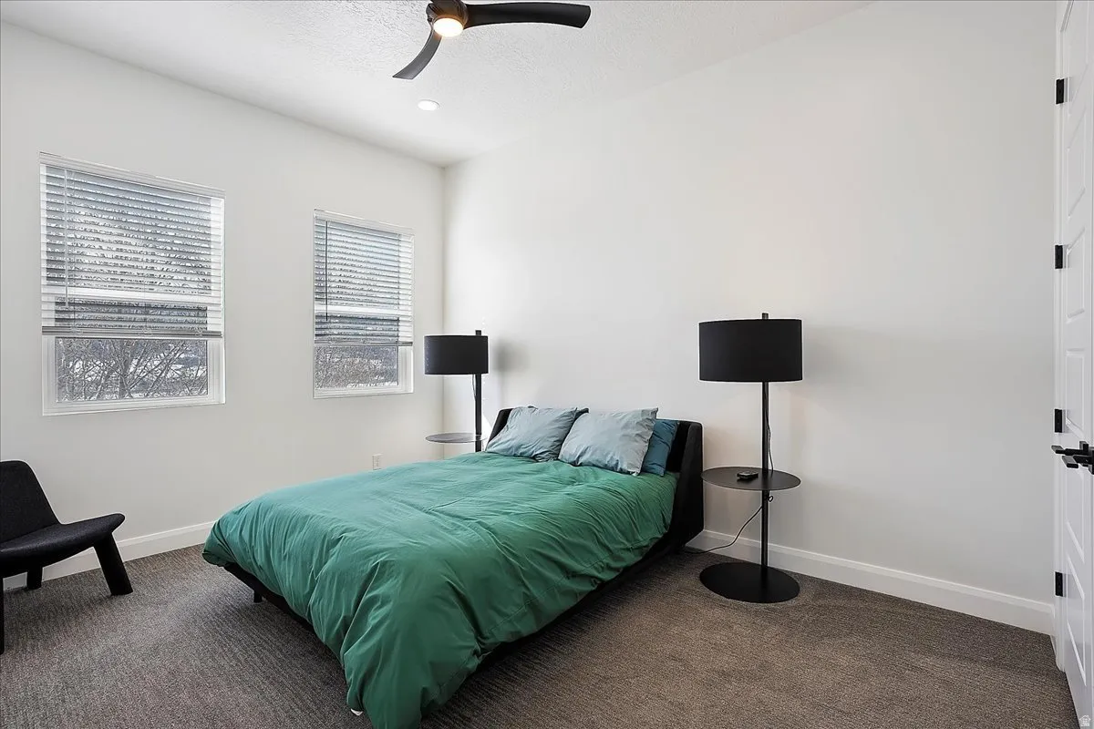 Bedroom with dark colored carpet, ceiling fan, and a textured ceiling