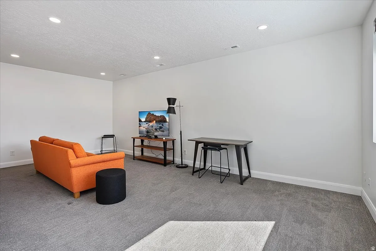 Living area featuring carpet, recessed lighting, and a textured ceiling