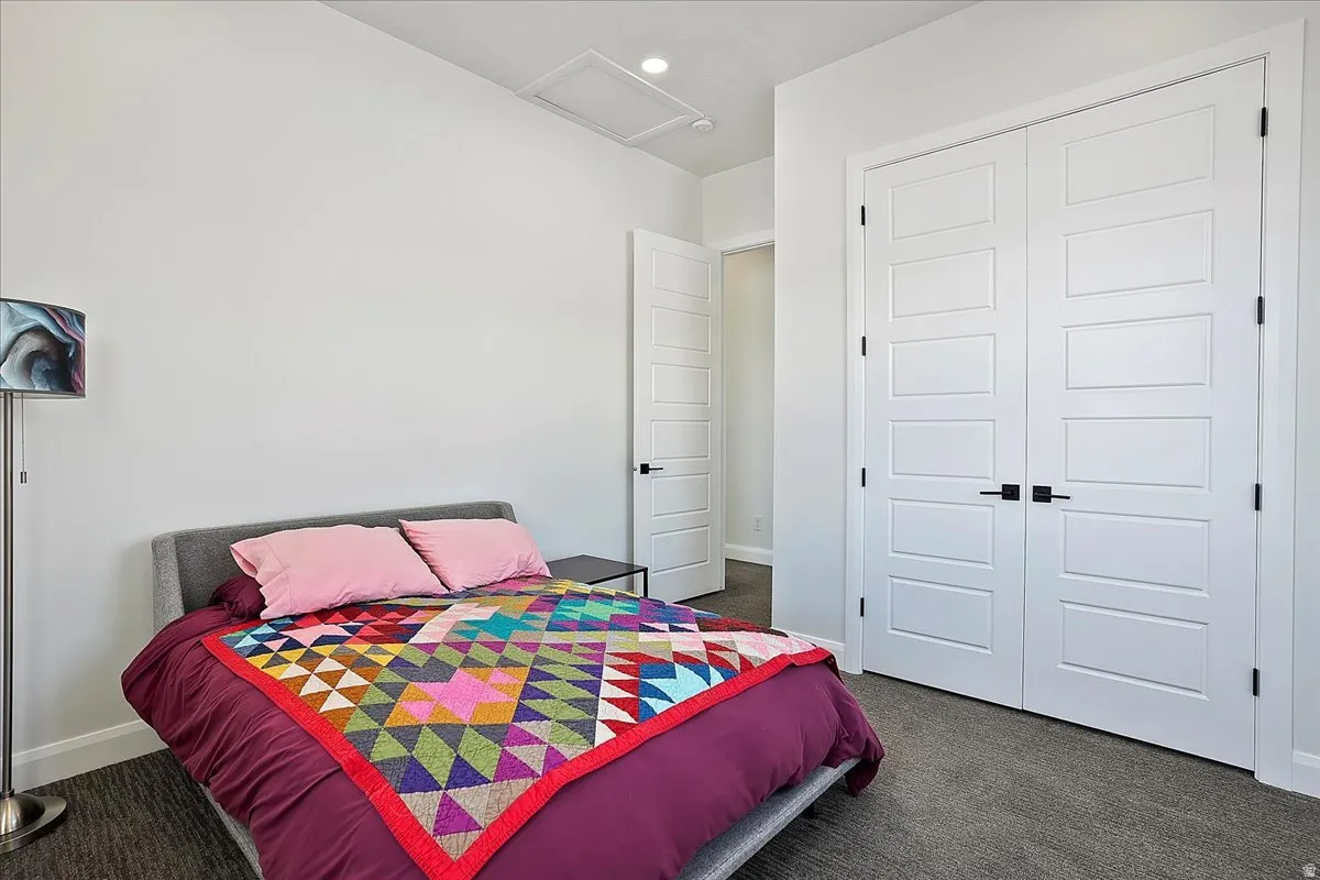 Bedroom with dark colored carpet, attic access, a closet, and recessed lighting