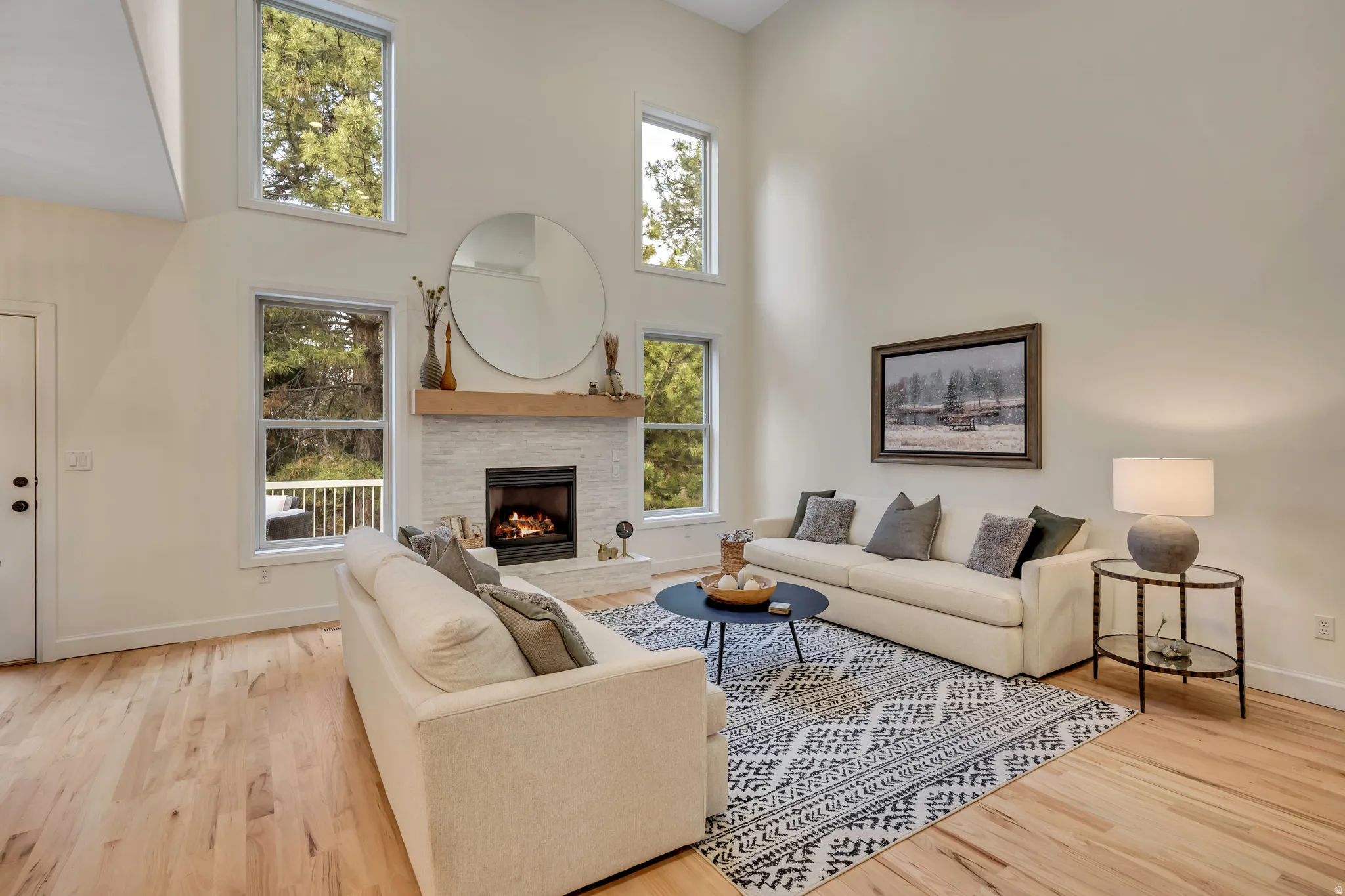 Living room with a high ceiling, healthy amount of natural light, a fireplace, and light wood-style flooring