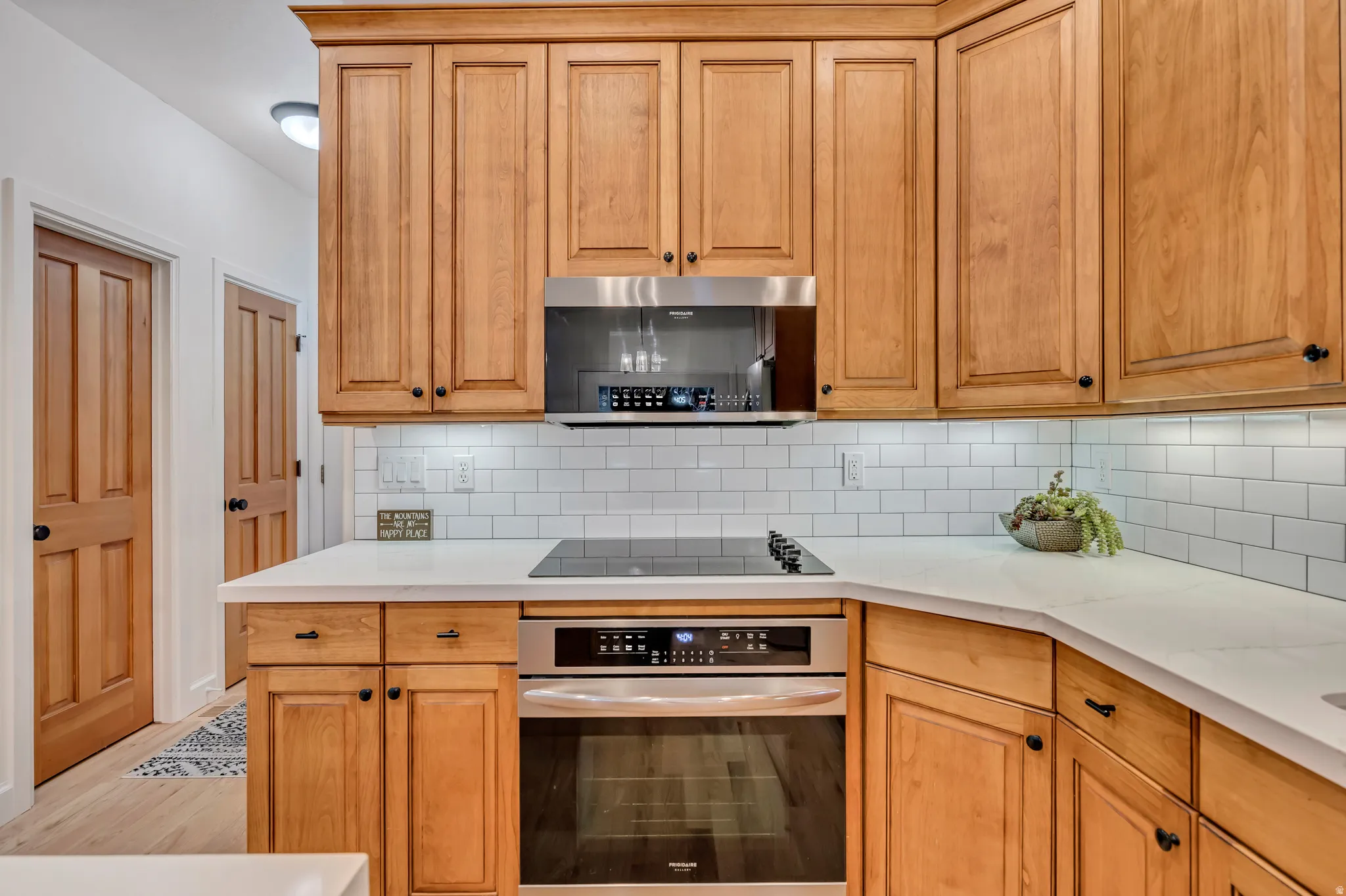 Kitchen with stainless steel appliances, tasteful backsplash, light stone counters, and light wood-type flooring