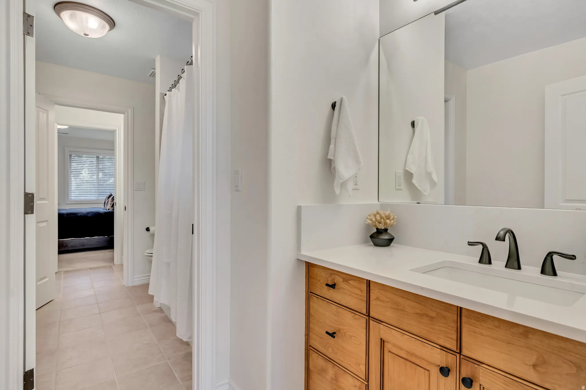 North vanity of Jack-n-Jill Full bathroom featuring vanity, a shower with curtain, light tile patterned floors, and connected bathroom