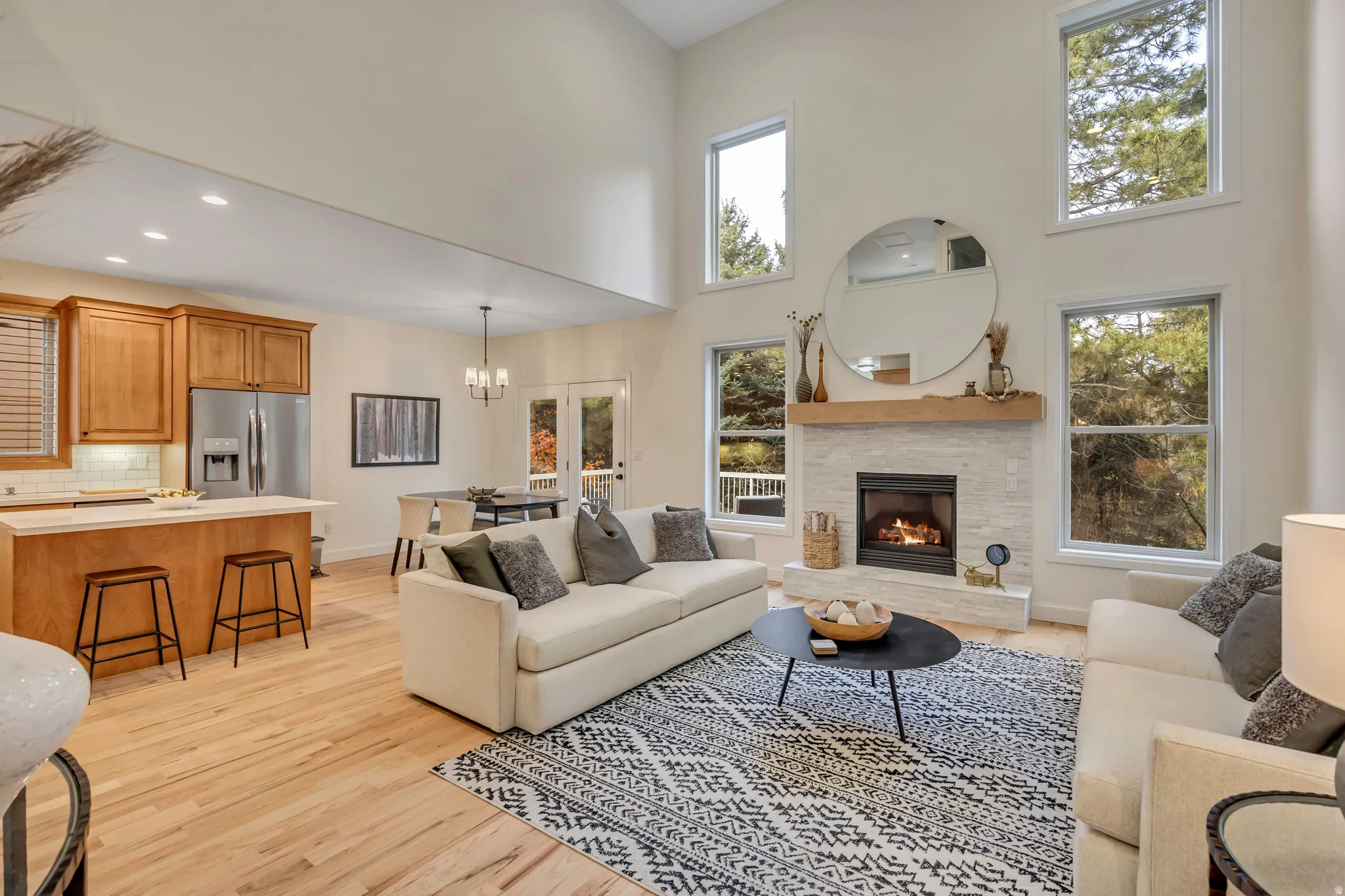 Living room featuring a chandelier, a towering ceiling, light wood-type flooring, a fireplace, and recessed lighting