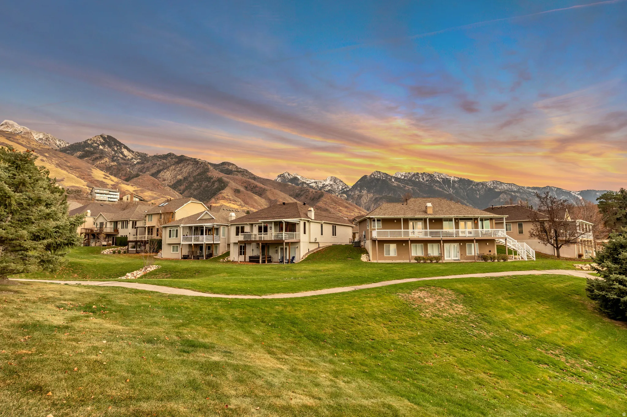 Common Space - View of front facade featuring a front lawn, a mountain view, stairs, a balcony, and a residential view