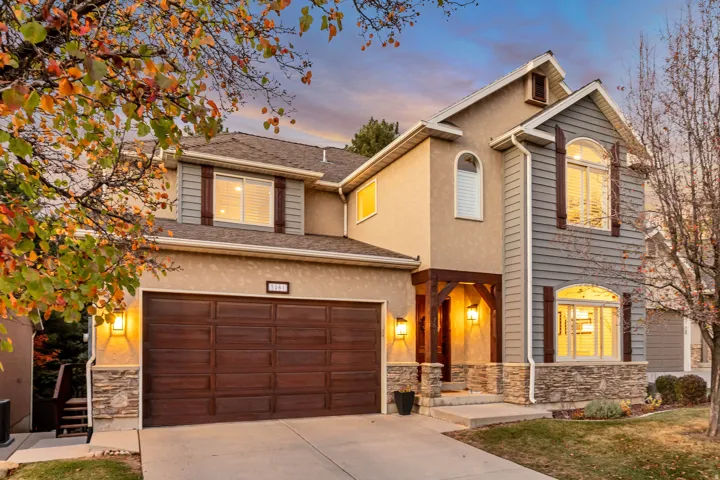 Traditional-style house with stone siding, concrete driveway, a garage, stucco siding, and a shingled roof