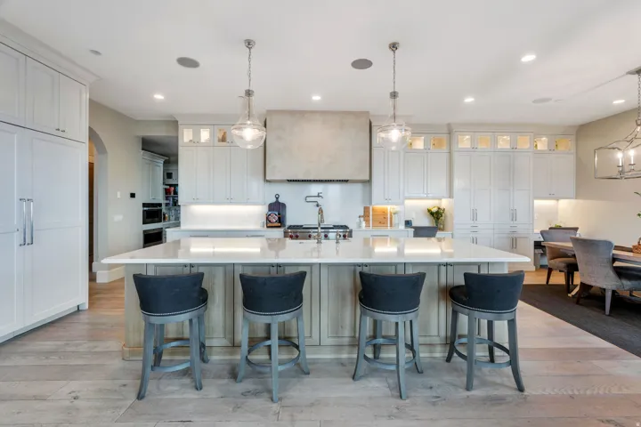 Kitchen featuring glass insert cabinets, hanging light fixtures, white cabinetry, a large island, and light wood-style flooring