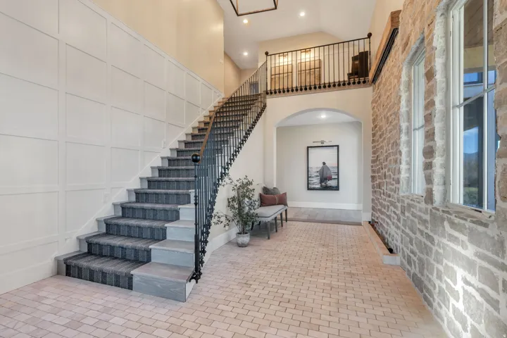 Staircase with high vaulted ceiling, recessed lighting, and arched walkways