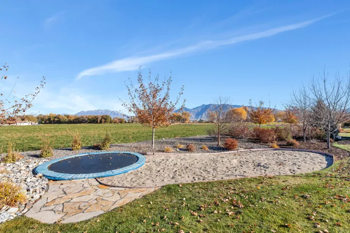 View of grassy yard with a trampoline and a mountain view