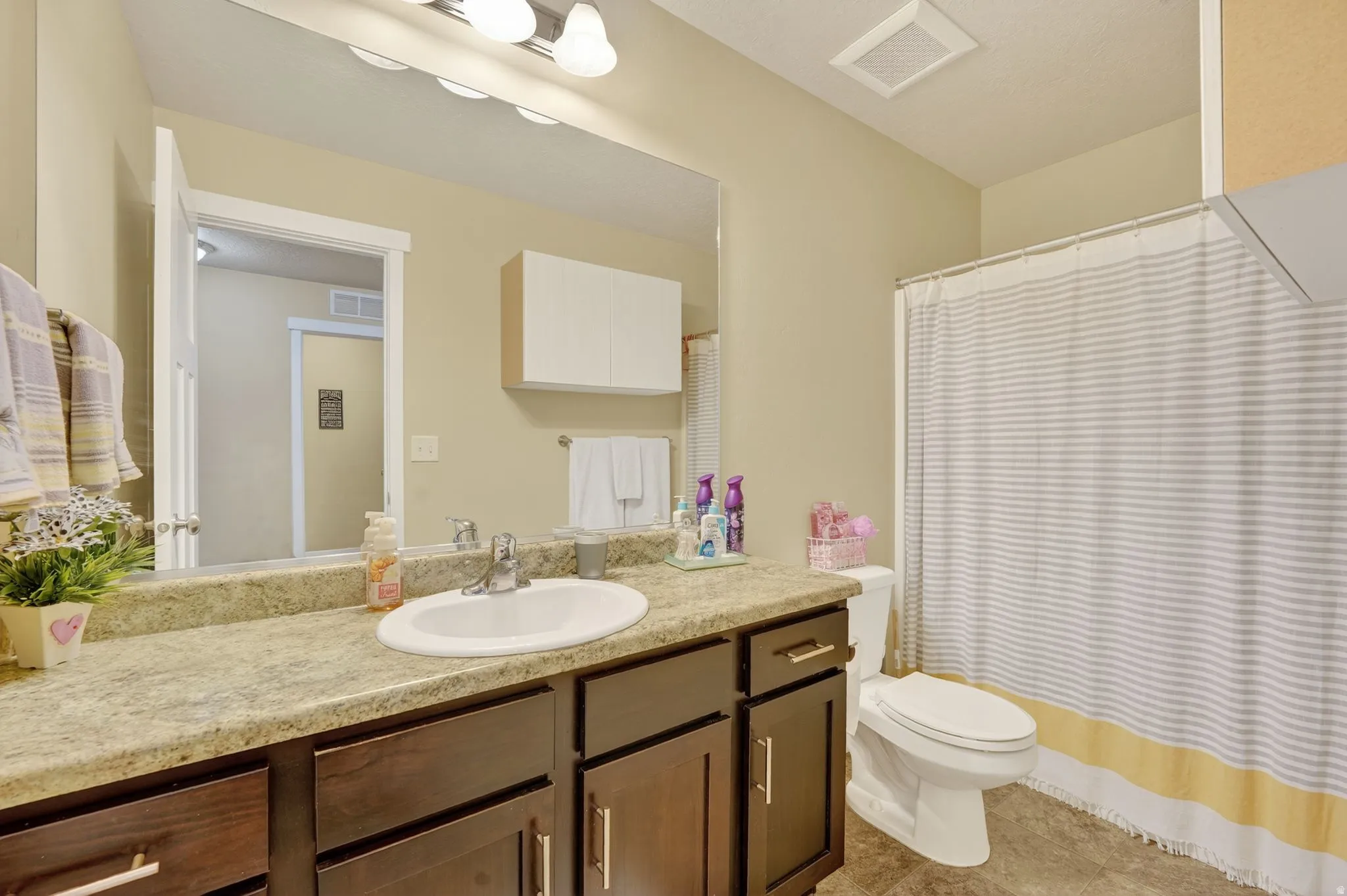 Bathroom featuring a shower with shower curtain, vanity, and light tile patterned floors