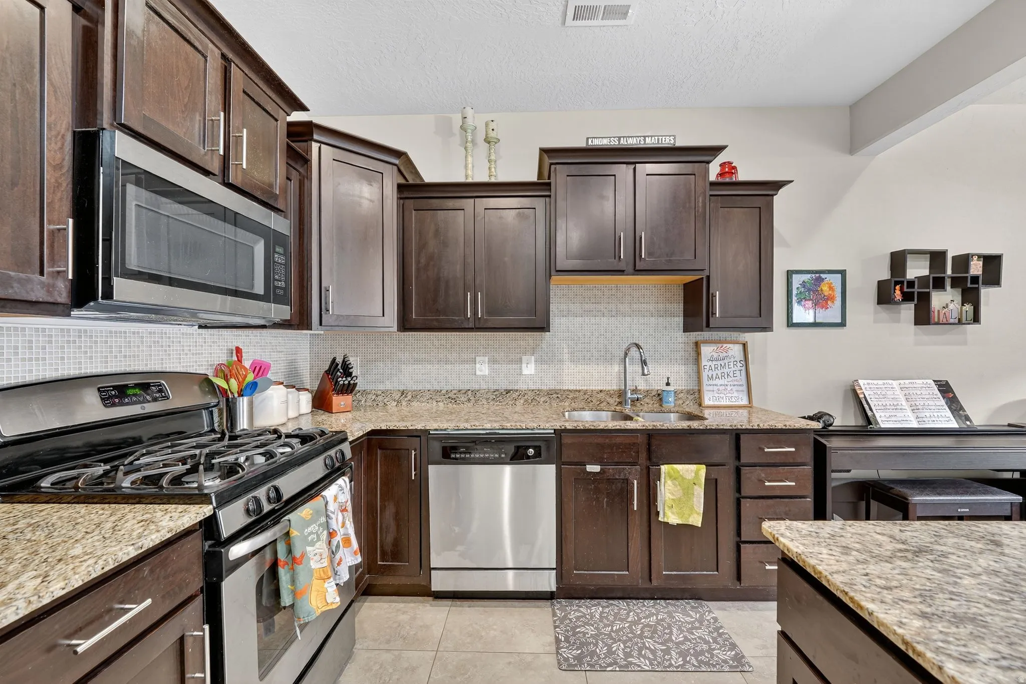 Kitchen with appliances with stainless steel finishes, dark brown cabinets, tasteful backsplash, and a textured ceiling