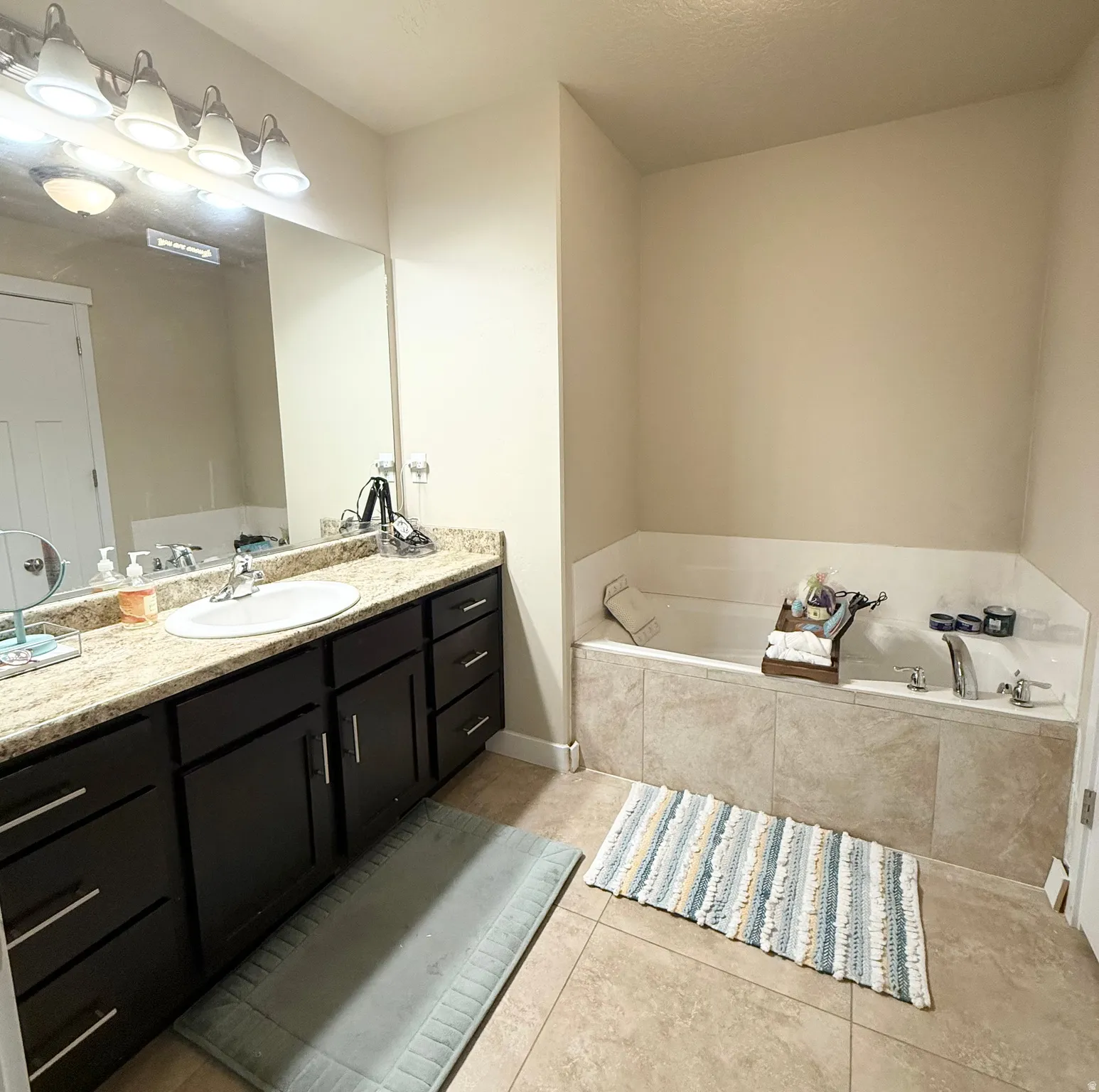 Full bath with light tile patterned floors, vanity, and a garden tub