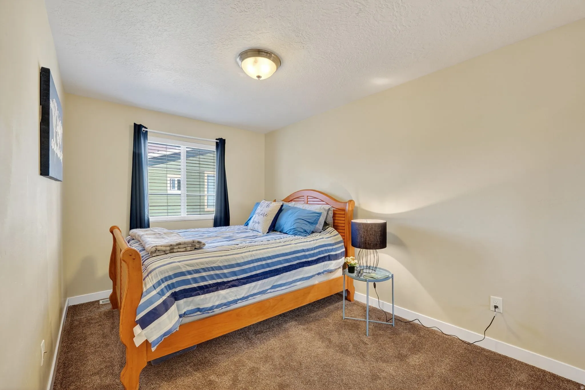 Carpeted bedroom with a textured ceiling and baseboards