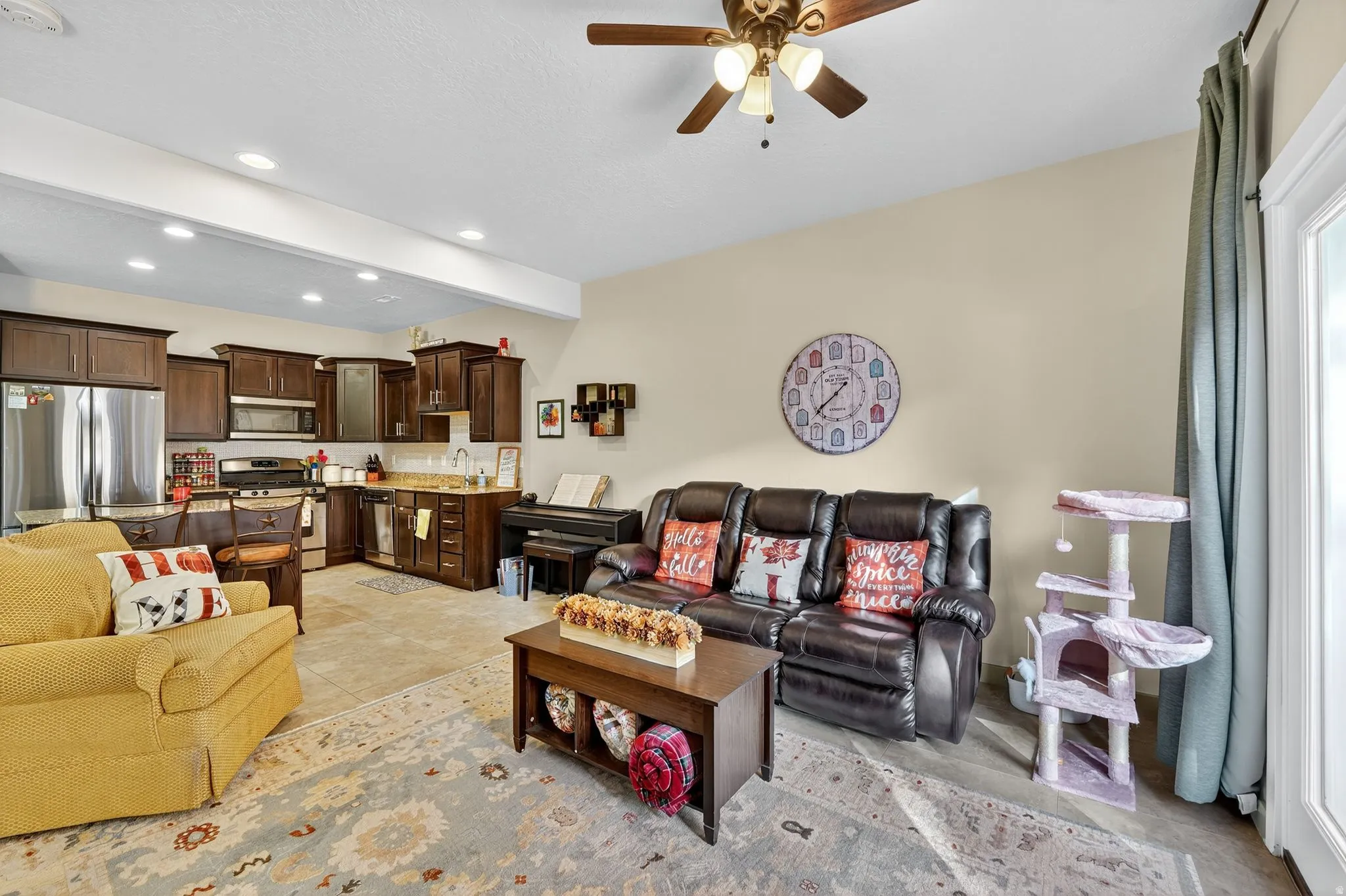 Living room featuring a ceiling fan, recessed lighting, light tile patterned flooring, and beam ceiling