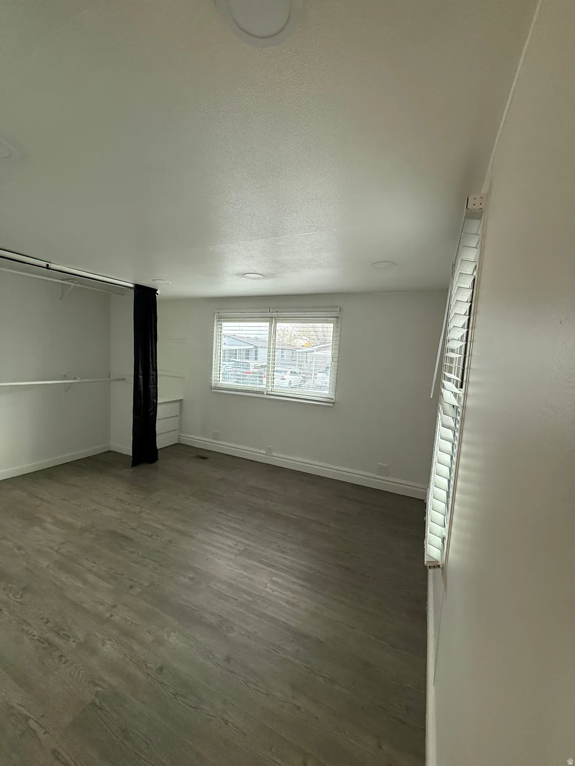 Unfurnished bedroom with dark wood-type flooring, a textured ceiling, and a closet