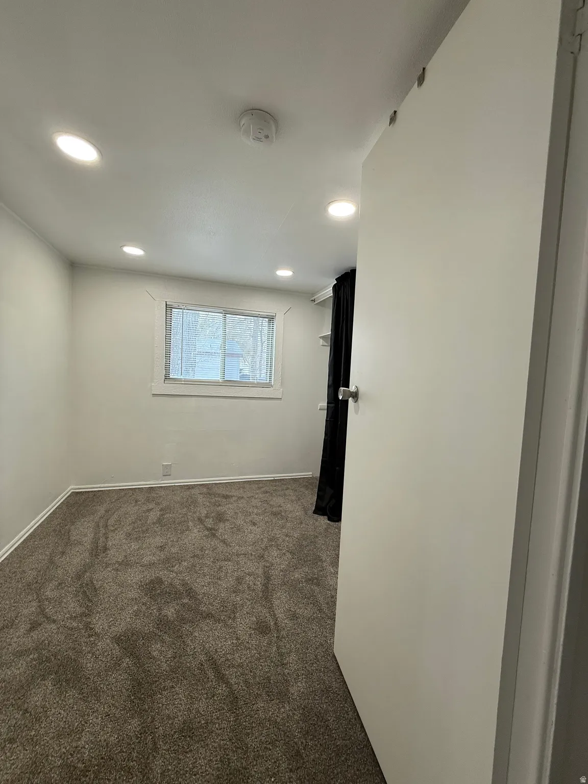 Empty room featuring dark colored carpet, recessed lighting, and a smoke detector