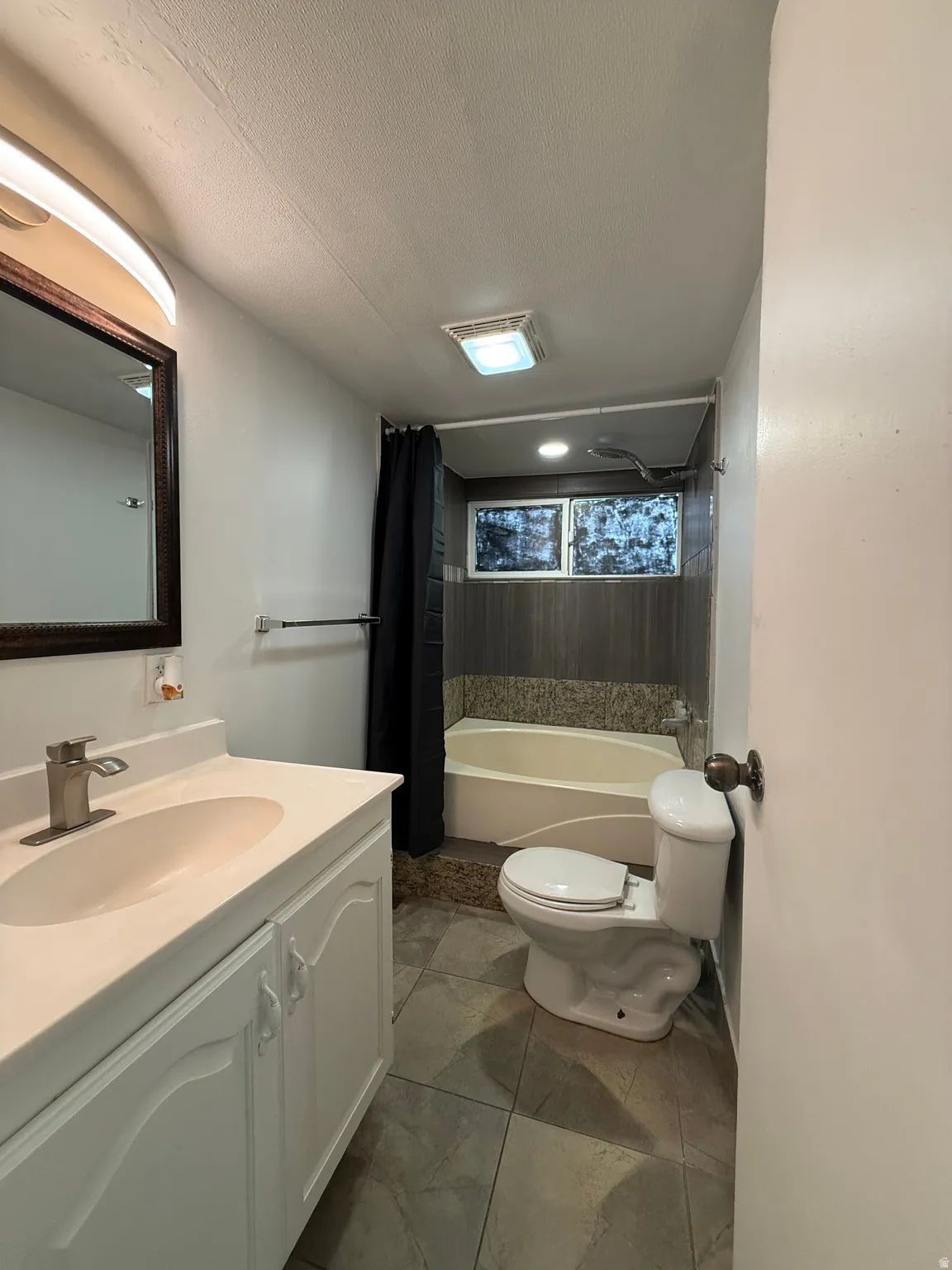 Bathroom featuring vanity, a textured ceiling, and shower / bath combination with curtain