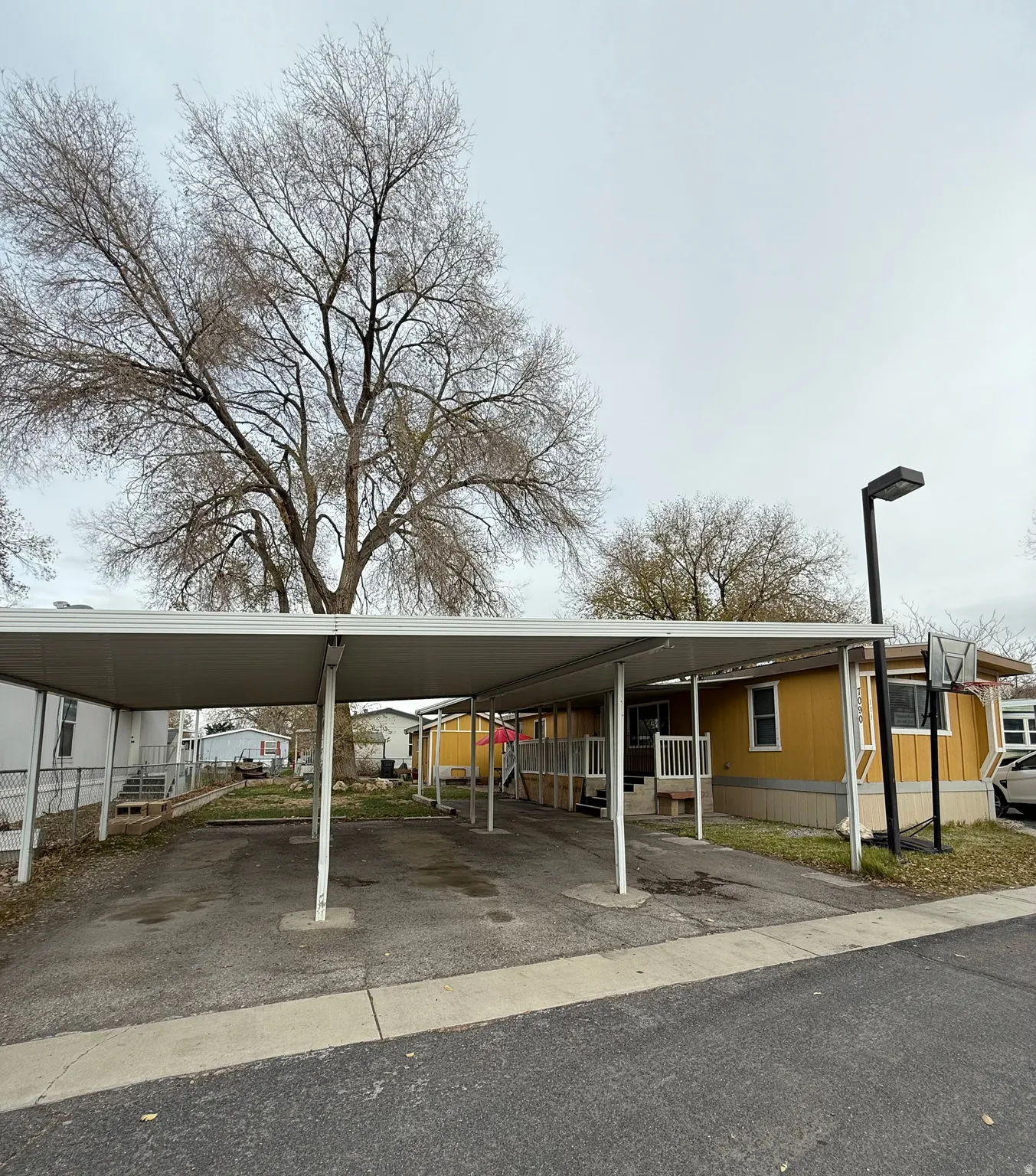 View of vehicle parking with a carport and asphalt driveway