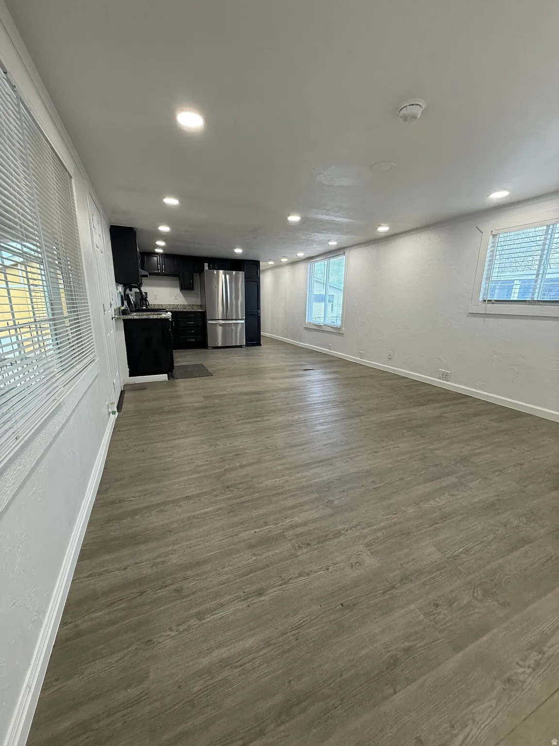 Unfurnished living room featuring dark wood finished floors, recessed lighting, and a textured wall