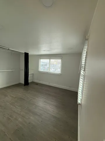 Unfurnished bedroom with dark wood-type flooring, a textured ceiling, and a closet