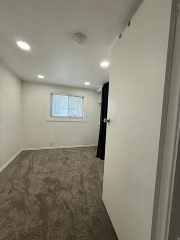 Empty room featuring dark colored carpet, recessed lighting, and a smoke detector