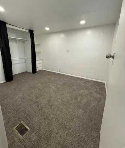 Unfurnished bedroom featuring dark colored carpet, recessed lighting, and a closet