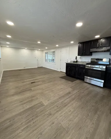 Kitchen featuring stainless steel gas range, dark cabinets, light wood finished floors, a textured ceiling, and recessed lighting