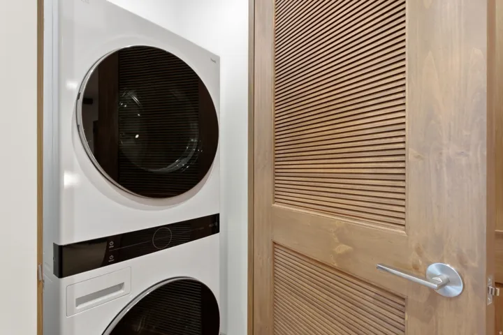 Stackable laundry appliances with sleek controls, wood louvered door, and satin nickel hardware