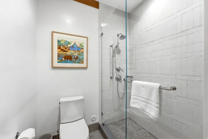 Glass-enclosed shower with a rainfall showerhead, tiled walls, and a tiled shower pan