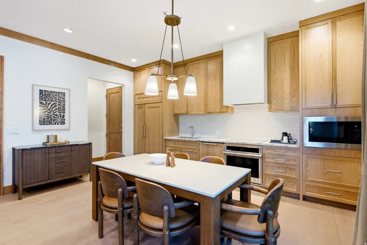 Kitchen featuring light wood-finish cabinetry, integrated stainless steel appliances, a white subway tile backsplash, and recessed lighting
