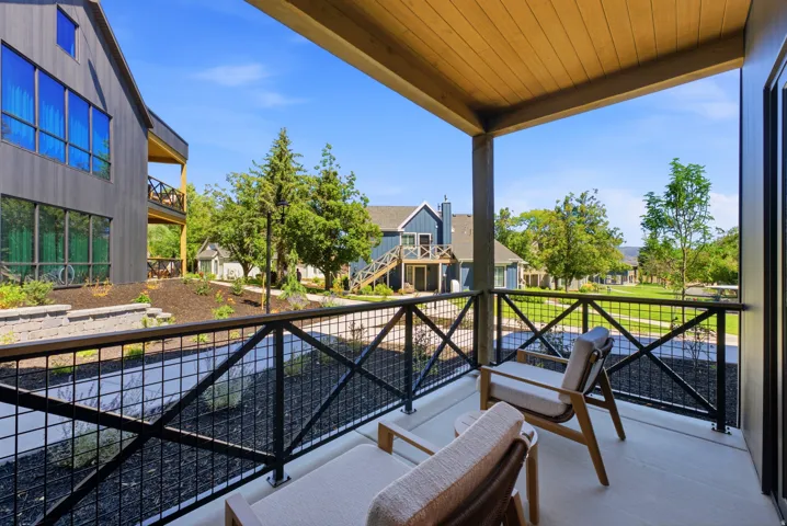Private balcony featuring a wood-finish ceiling, concrete flooring, and black metal railings with cross detailing