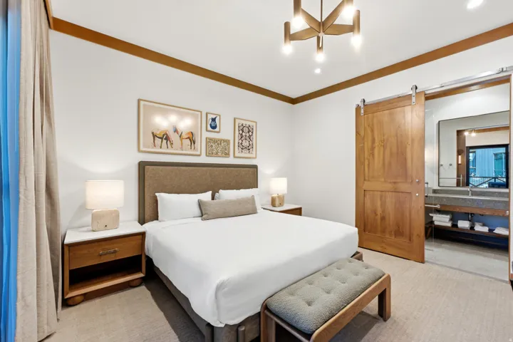 Wood-finish accent trim, overhead chandelier, and built-in bedside tables with white stone tops