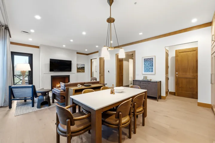Open-concept living space featuring wood-finish flooring, a white mantel fireplace, recessed lighting, a modern chandelier, and wood trim accents