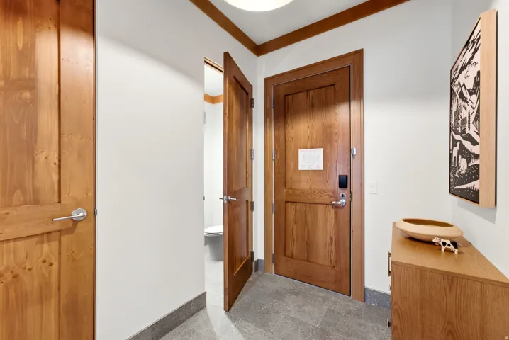 Wood-finish interior doors with brushed nickel hardware, perimeter wood-finish trim, and tile flooring