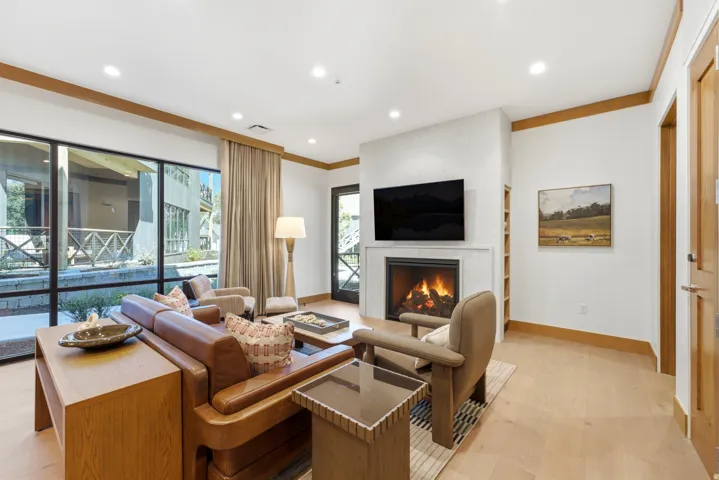 Expansive floor-to-ceiling windows, wood-finish flooring, built-in fireplace, recessed lighting, and integrated shelving