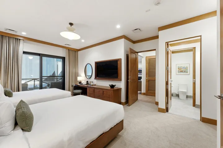Carpeted bedroom with wood-finish trim, a mounted television, and direct access to a private balcony
