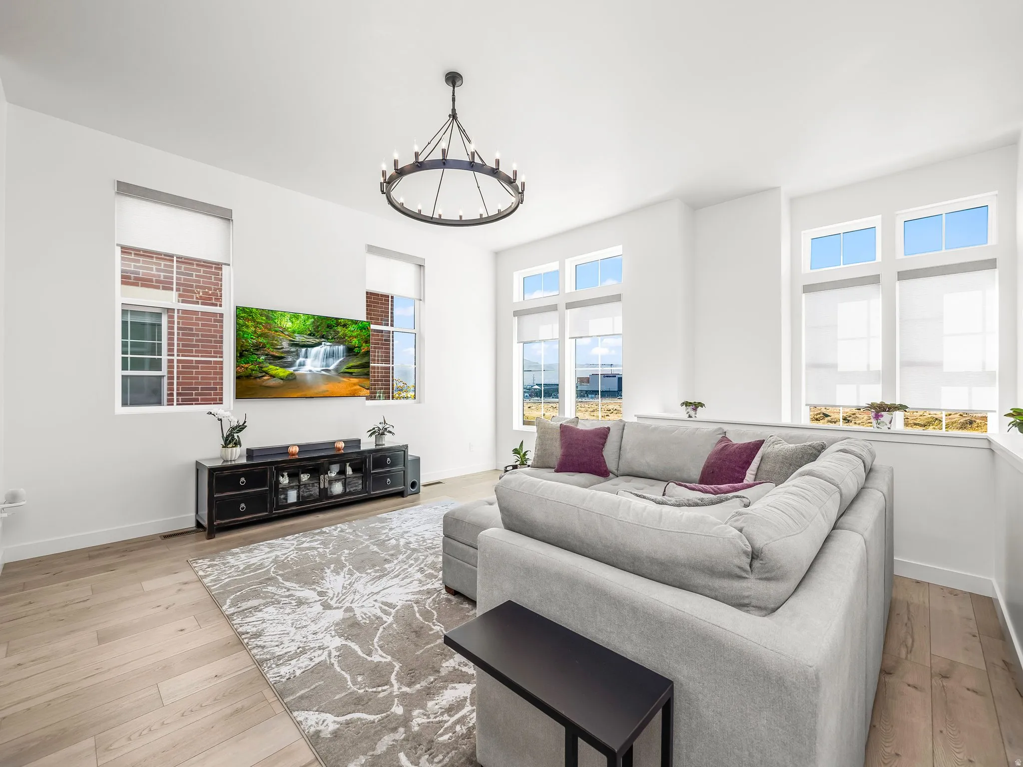 Living room with plenty of natural light, light wood-style floors, and a chandelier