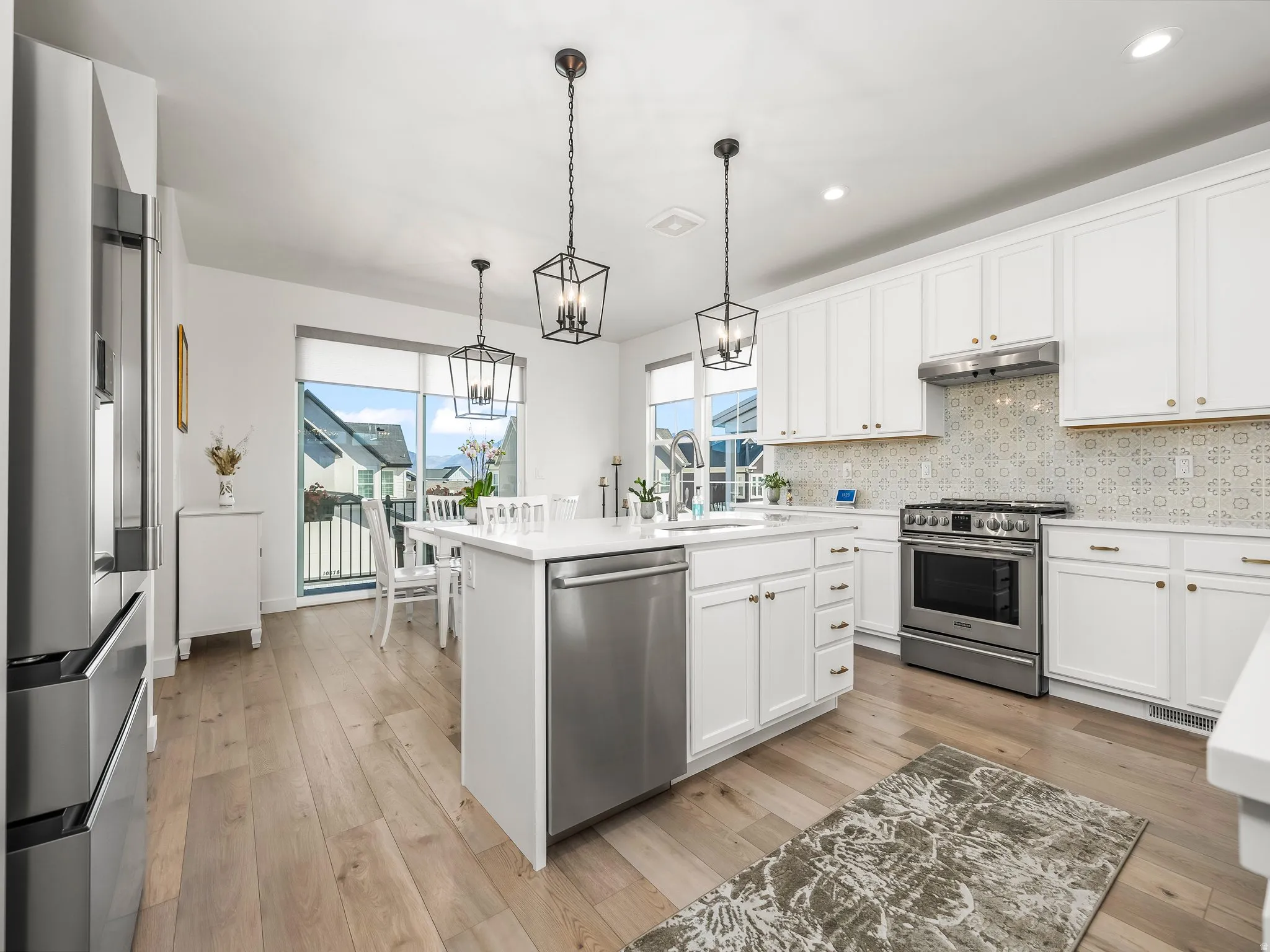 Kitchen featuring white cabinetry, stainless steel appliances, decorative light fixtures, tasteful backsplash, and healthy amount of natural light