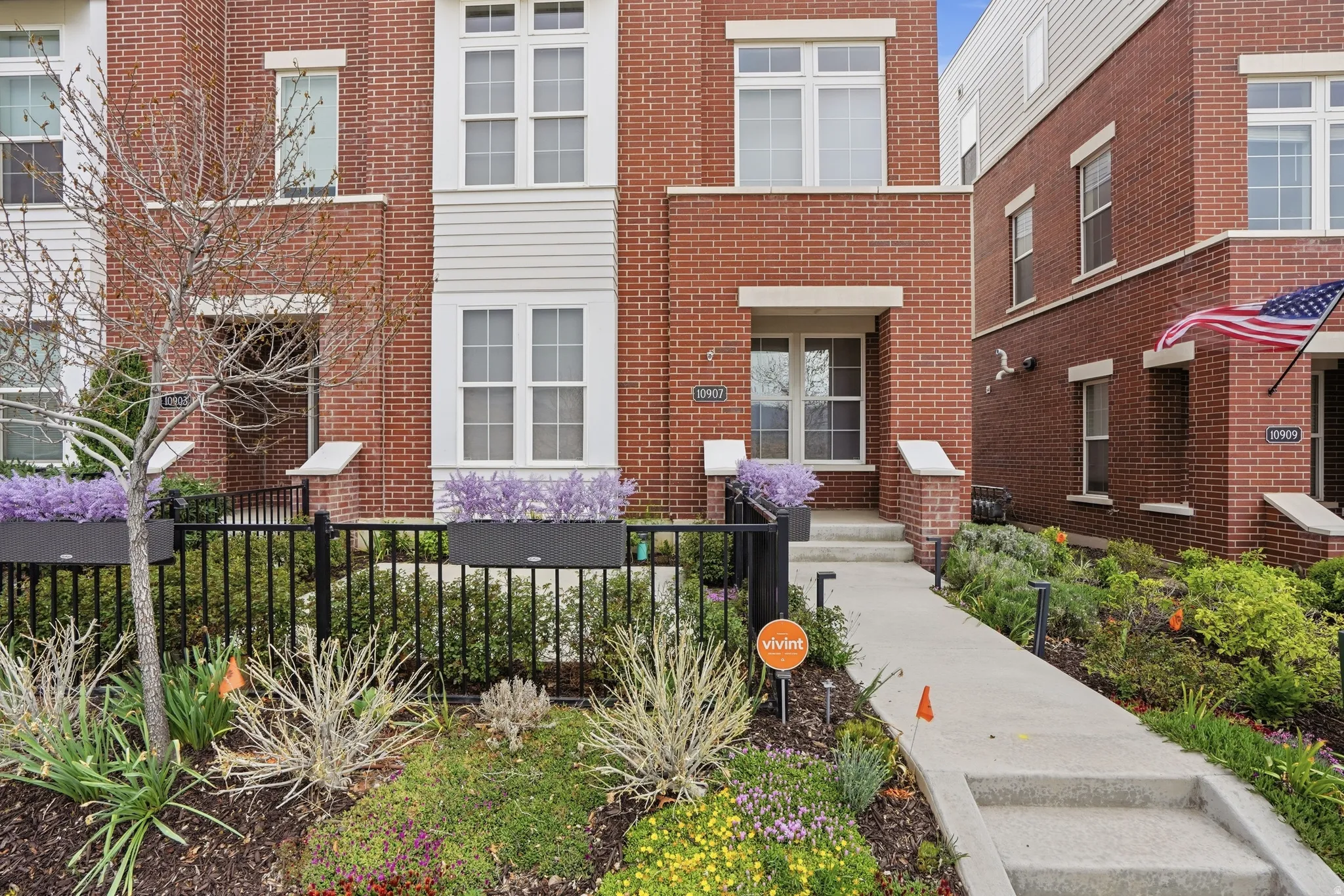 Brick facade townhome with white window trim and a concrete pathway