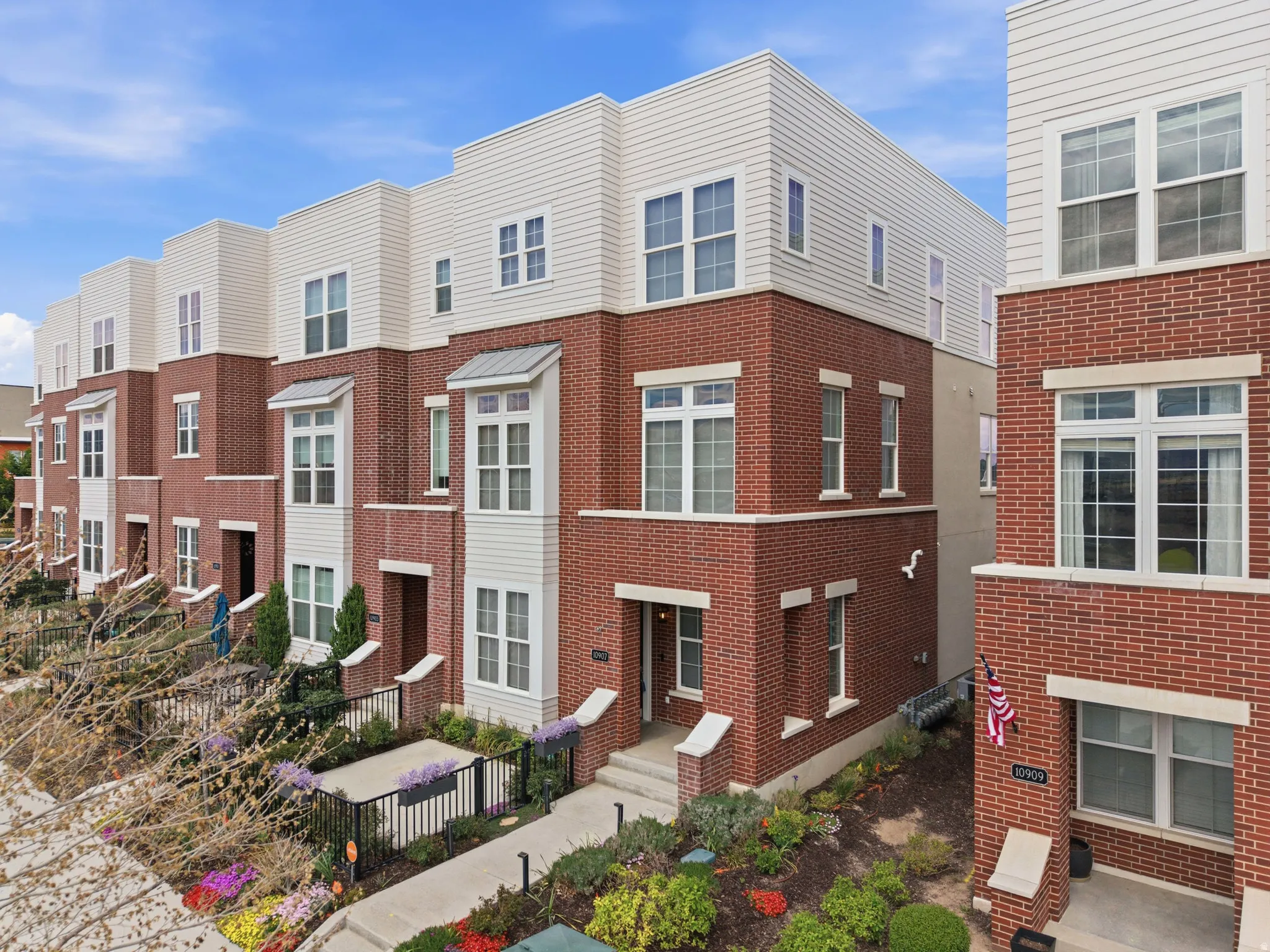 Contemporary multi-level townhome featuring a brick and siding facade with prominent bay windows