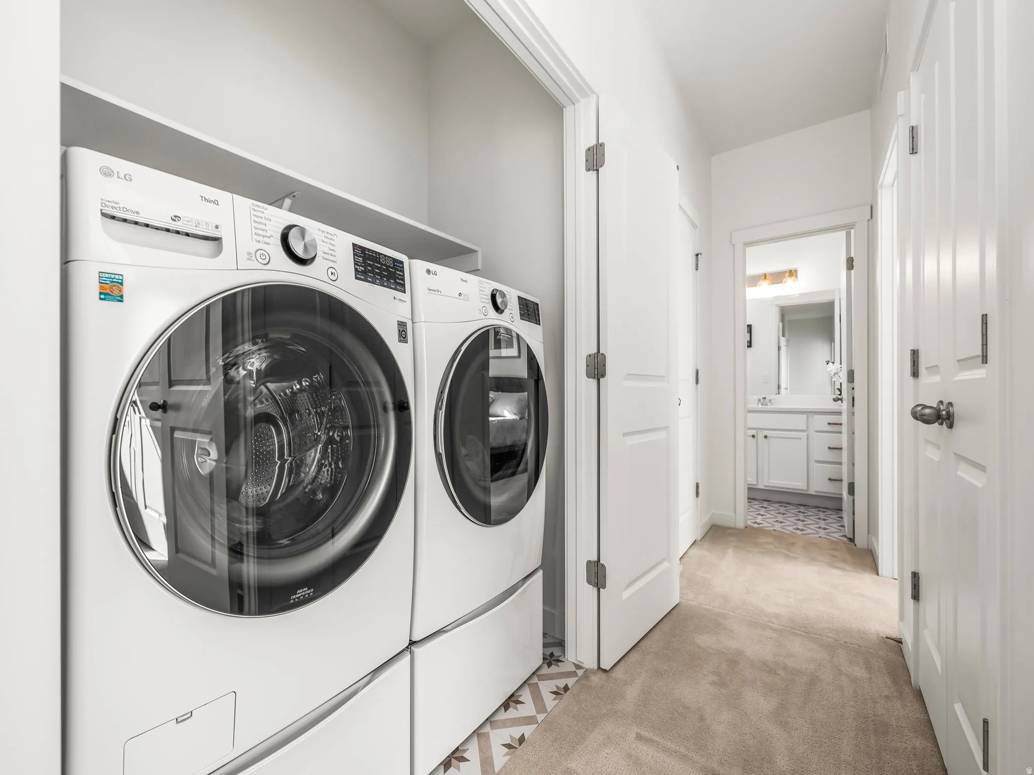 Laundry room featuring light carpet and washer and dryer